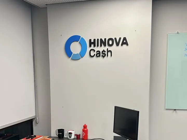 Logotipo Hinova Cash em letra caixa na parede de uma sala