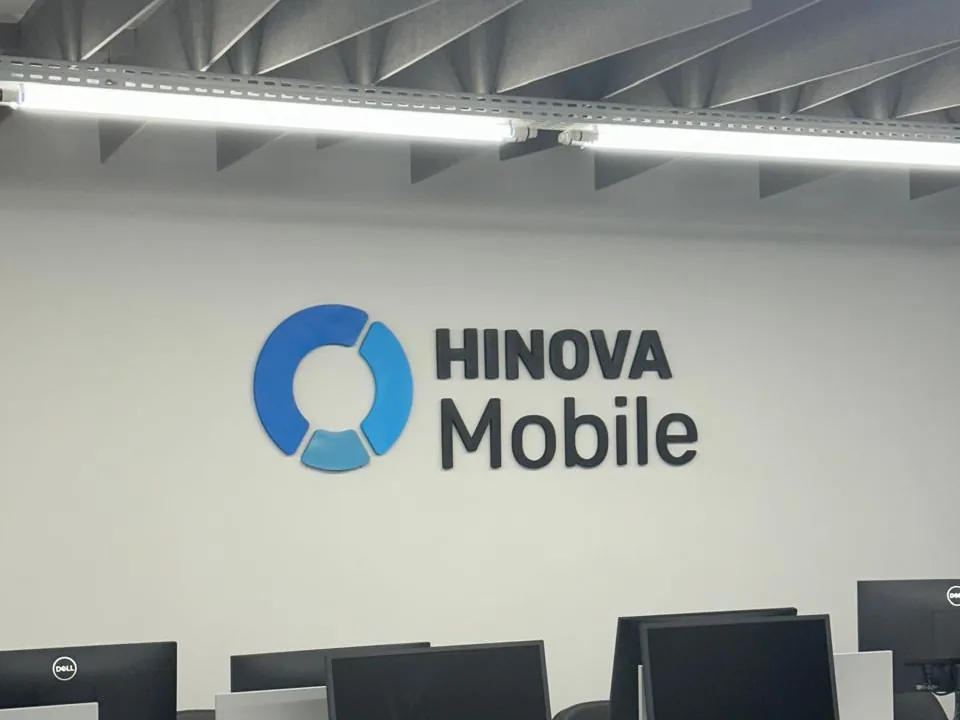 Logotipo Hinova Mobile em letra caixa na parede do salão de trabalho